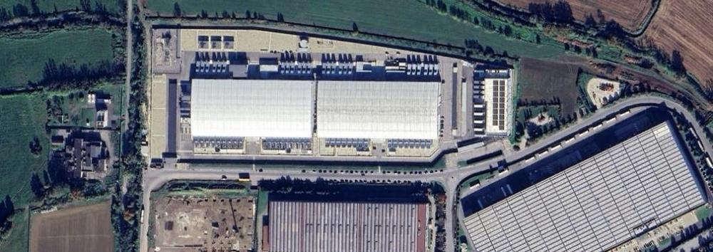 Lo stesso luogo nel 2025: al posto dei campi c’è un grande data center con due edifici bianchi e piazzali